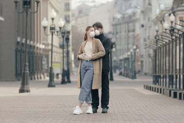 Young couple in love in the empty streets in medical masks. Virus protection concept