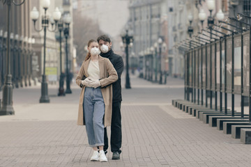 Young couple in love in the empty streets in medical masks. Virus protection concept