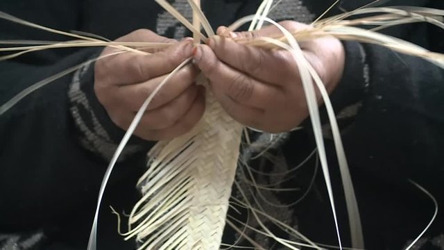 Hands starting an object out of palm leaves.Workshop of Tunisian arabic women weaving traditional goods from palm leaves.