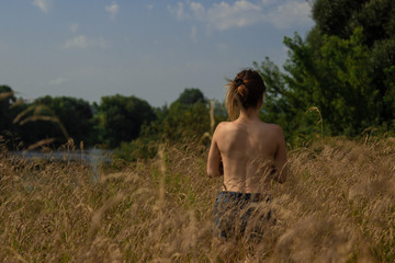 Girl stands with his back in the field
