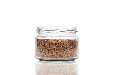 glass jar with flaxseeds on a white background, selective focusing