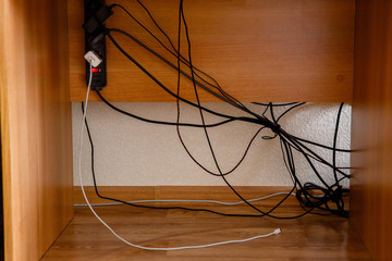 Surge Protector, charger, tangled wires and cable under the table