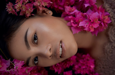 Asian girl portrait face in pink flowers. Beautiful Balinese women. Beauty salon and massage spa concept