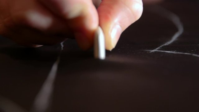 handsome male suit tailor hand with chalk trace on fabric along ruler on desktop. Designer master works in workshop clothing factory.