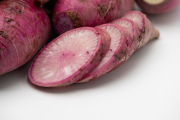 Pile of whole and sliced purple daikon radish isolated on white background