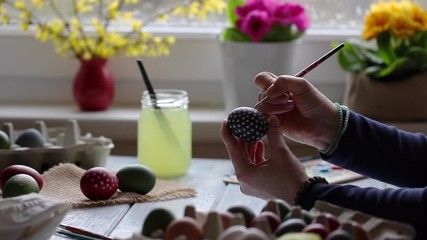 Woman painting and decorating eggs for Easter holiday