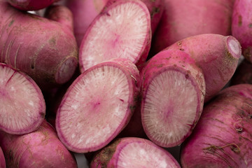 Pile of whole and sliced purple daikon radish isolated on white background