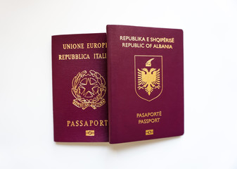 Holding two different nationalities passports in a hand on a white background - Albania and Italy countries - Boarding , trevelling and documents