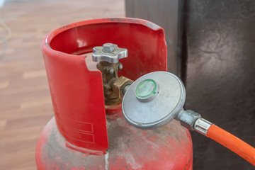 Connecting hose with flap to gas cylinder, red gas cylinder close-up