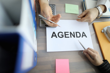 Top view of businessman and businesswoman hands holding pens. Colleagues planning work for future. Order paper and stickers for note on table. Business and agenda concept