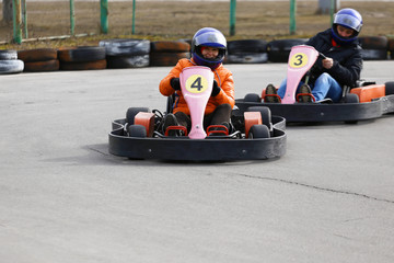 girl is driving Go-kart car with speed in a playground racing track.