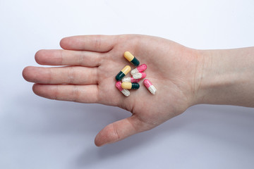 hand with different capsules and tablets of drugs for the treatment of the virus and diseases
