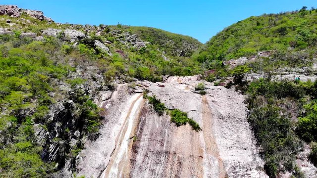 Cinematic aerial shot of conceicao dos gatos waterfall. Tourists relaxing, swimming and enjoying the sun. Chapada Diamantina, Bahia, Brazil. Drone moving Forward and up.