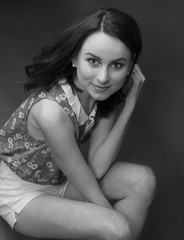 Black and white portrait of a stunning sexy young brunette on a gray background, a floral blouse and white short shorts. Close-up. Beauty and Fashion