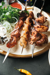 Beef skewers on pita bread on a wooden board, red sauce, marinated onions, side view, horizontal, Caucasian cuisine