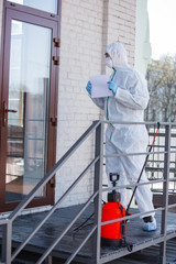 Coronavirus Pandemic. A disinfector in a protective suit and mask sprays disinfectants in house or office. Protection agsinst COVID-19 disease. Prevention of spreding pneumonia virus with surfaces.