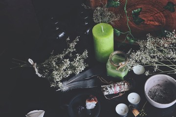 Various enchanted spell work ingredients on wiccan witch altar. Messy clutter on black table, with...