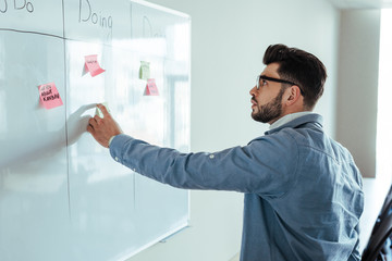 Scrum master looking at white board with spreadsheet and stickers