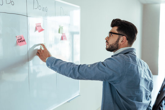 Scrum Master Looking At White Board With Spreadsheet And Stickers