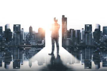 Fototapeta na wymiar The double exposure image of the businessman standing back during sunrise overlay with cityscape image. The concept of modern life, business, city life and internet of things.