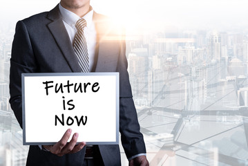 The abstract image of the businessmen holds a whiteboard and text wrote "Future is now" during sunrise overlay with cityscape image. The concept of insurance, business, health care and emergency.