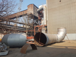 A huge chimney pipe in the factory lies on the ground before installation on the unit. End view