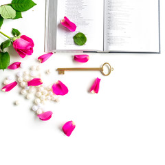 Pink Bible flat lay: Pearls, pink rose petals, open book and golden key on white bright background. Morning devotional with pink roses. Top view. Baselland, Switzerland - 22.11.2019