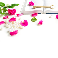 Pink Bible flat lay: Pearls, pink rose petals, open book and golden key on white bright background. Morning devotional with pink roses. Top view. Baselland, Switzerland - 22.11.2019