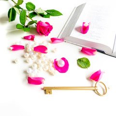 Obraz na płótnie Canvas Pink Bible flat lay: Pearls, pink rose petals, open book and golden key on white bright background. Morning devotional with pink roses. Top view. Baselland, Switzerland - 22.11.2019