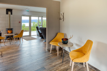 Modern design lounge of a family atmosphere hotel with dark leather sofas and wooden tile floor. Natural and ambient light. Scandinavian style.
