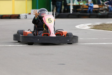 boy is driving Go-kart car with speed in a playground racing track.