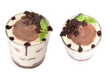 tiramisu in a glass with berries, mint and coffee beans on a light wooden background