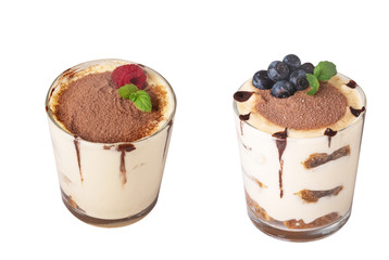 tiramisu in a glass with berries, mint and coffee beans on a light wooden background