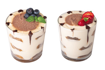 tiramisu in a glass with berries, mint and coffee beans on a light wooden background