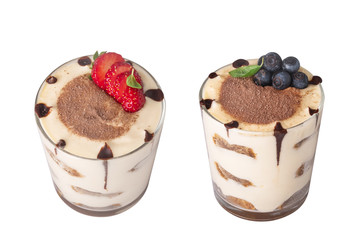 tiramisu in a glass with berries, mint and coffee beans on a light wooden background