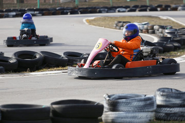 girl is driving Go-kart car with speed in a playground racing track.