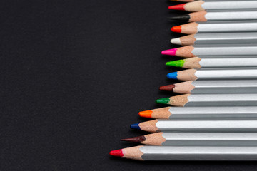 Naklejka premium gray wooden pencils with colored rods on a black background