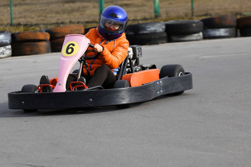 girl is driving Go-kart car with speed in a playground racing track.