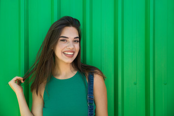 Trendy young woman standing by the green wall