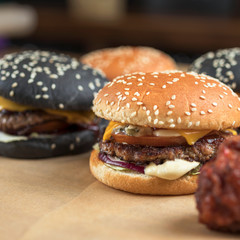 hamburgers with yellow and black rolls on parchment paper with breaded chicken wings and French fries