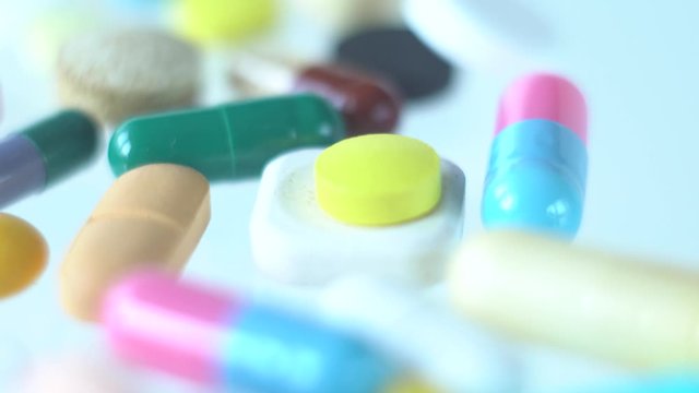 Dolly movement over colorful assorted pills and drugs on white background.