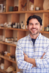 Portrait Of Male Owner Of Gift Store Standing In Front Of Shelves With Cosmetics And Candles