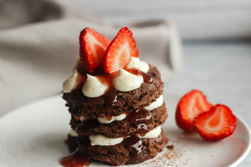 Tasty cake with cream and strawberries on a plate. Chocolate sponge cake, delicate cream cheese and raspberry filling. Strawberry decoration on top