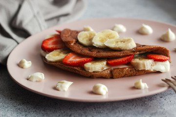 Delicious banana oatmeal pancake on a plate. Oatmeal pancake with cream cheese, banana and strawberries