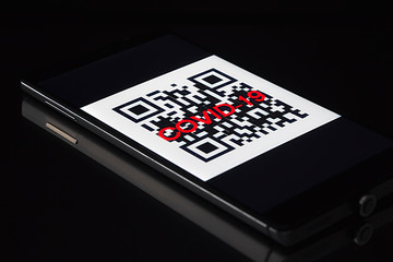 QR code with the inscription COVID-19 on the display of a mobile phone on black background. cityzens must show code to  police to move in the city during quarantine while pandemic of corona virus
