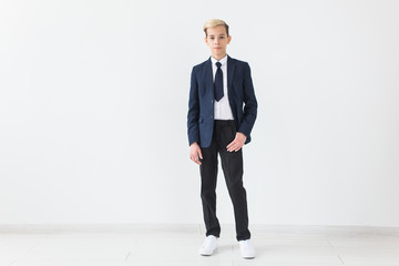 Portrait of stylish school boy teenager in white shirt and jacket against white background.