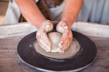 Potter's wheel with clay. Women's hands make a vase of clay.