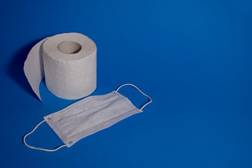 White mask and toilet roll on a blue background.