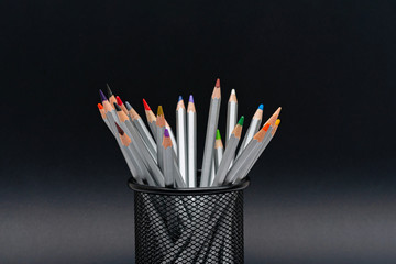 gray wooden pencils with colored rods  in the stand on a black background