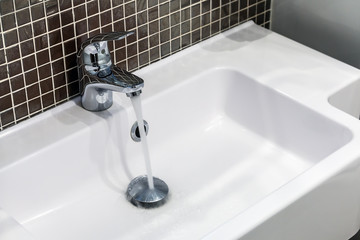 chrome faucet with running water in the toilet or bathroom